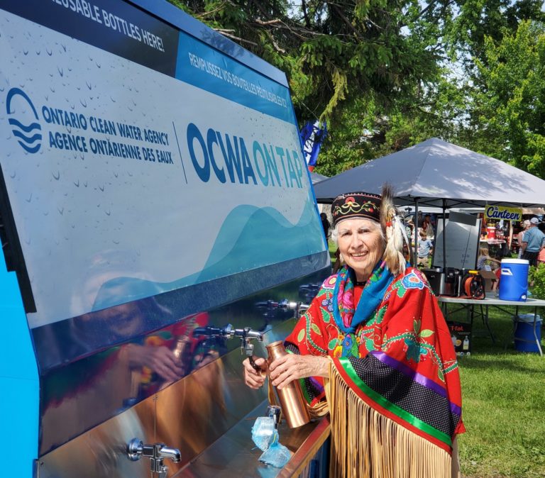 Woman filling up a bottle at a OCWA portable water unit